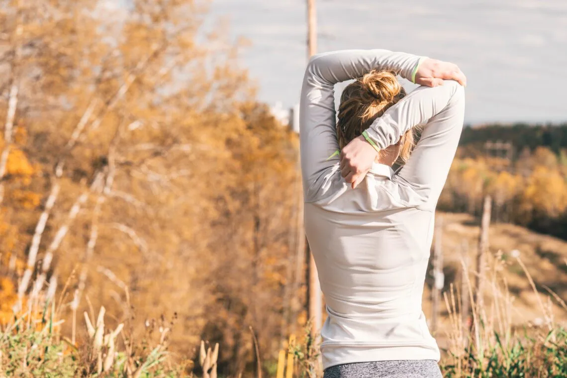 Woman stretching outdoors in autumn - staying active alongside BodyTite body contouring